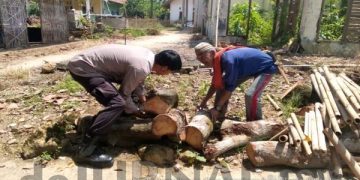 Seorang Bhabinkamtibmas Dengan CAKEP Bantu Lansia Yang Angkut Kayu Berat