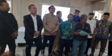 Pria pengantar paket (bertopi dan pegang map), sedang membacakan permintaan kepada DPRD Karawang. (Foto : Syarif Hidayat)